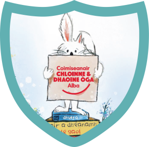 A cartoon bunny holding up a sign in Gaelic that says 'Coimiseanair Chloinne & Dhaoine Oga Alba' while standing on books. The bunny is framed by a light blue shield